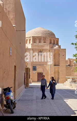 Yazd, Iran - April 21, 2017: A pair of elderly Iranian tourists walking near the clay buildings in the old town. Stock Photo