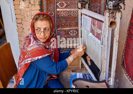 Yazd, Iran - April 21, 2017: One unknown woman weaver making persian rug in workshop. Stock Photo
