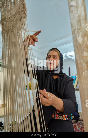 Yazd, Iran - April 21, 2017: One Iranian woman weaves a Persian carpet by hand. Stock Photo