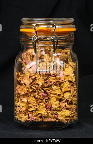 dried rose petals in a glass jar with lid on a black background Stock Photo