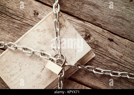 Chained book on wooden background