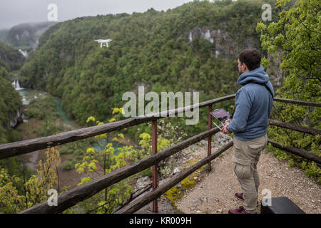 Man is operating the drone with a Plitvice waterfalls background Stock Photo