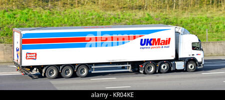 Red white and blue UKMail express parcels & mail articulated delivery trailer & hgv distribution lorry truck transporting mail on English UK motorway Stock Photo