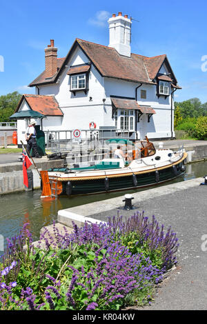 Goring Lock & keeper cottage River Thames with summer flowers & motor launch waiting to exit hydraulic gates blue sky sunny day Oxfordshire England UK Stock Photo