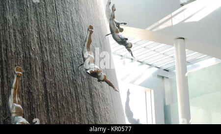 DUBAI, UAE - MAY 2, 2017: Famous Waterfall in Dubai Mall. A diver at The Waterfall inside the Dubai Mall. World's largest shopping mall. Fiberglass sculptures of human divers. Stock Photo