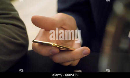 Man holding the golden smartphone. A golden color smartphone was held by hands busy updating in social networks Stock Photo