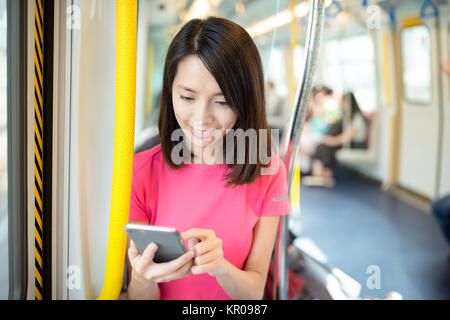 Young woman looking at cellphone inside train compartment Stock Photo