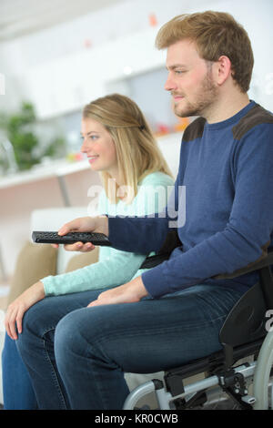 Disabled man watching TV with his girlfriend Stock Photo