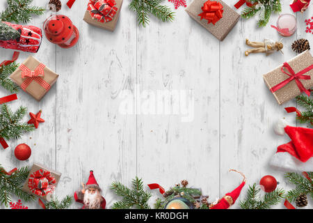 Christmas background on white wooden desk with Christmas tree, gifts, dolls, balls, Santa hat, candles, lantern, pinecones. Top view. Stock Photo