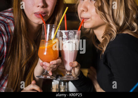 Young woman drinking milkshake while sitting with friends at cafe Stock Photo