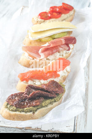 Crostini with different toppings on the wooden background Stock Photo