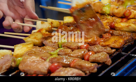 Thai street vendor sells pork satay - bbq fried pork meat on sticks. Stock Photo
