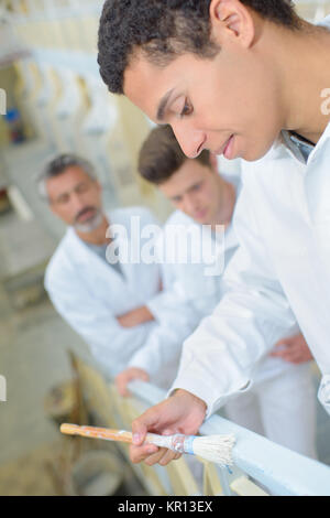 Apprentice painting railing Stock Photo