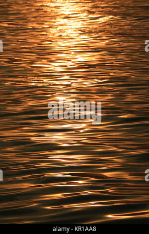 Golden sparkling morning sunlight reflections on the sea water surface with gentle ripples Stock Photo