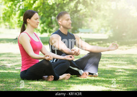 Couple Doing Yoga In Park Stock Photo
