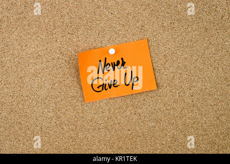 Never Give Up written on orange paper note Stock Photo
