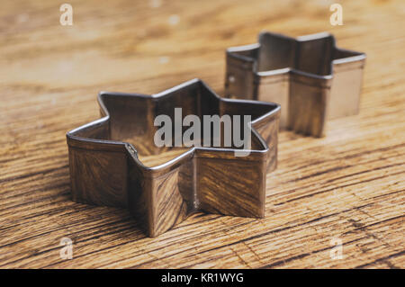 Two star shaped pastry cutters lying on a old wooden table. These pastry cutters are used to make traditional christmas cookies Stock Photo