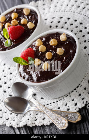 Chocolate pudding with hazelnuts and raspberry sauce in a bowl on the table. vertical Stock Photo