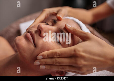 Close up of a woman having facial beauty treatment at spa salon. Beautiful young woman getting a face massage. Stock Photo