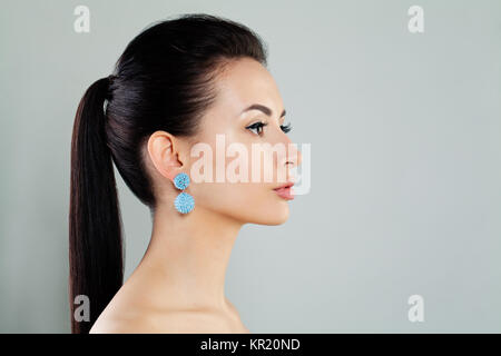 Closeup Fashion Portrait of Beautiful Model Woman wearing Blue Earrings. Pretty Young Face Stock Photo