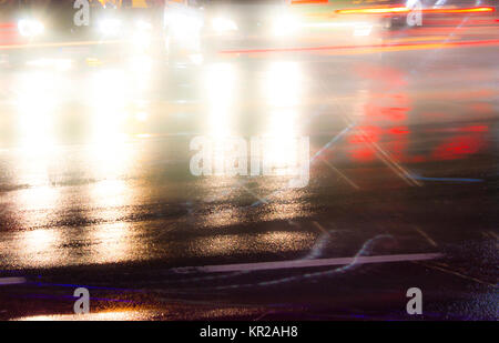 Blurry night traffic on rainy city streets intersection with light trails and reflections on wet asphalt. Stock Photo