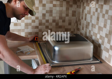 A Kitchen sink installation by a master in the kitchen. Stock Photo