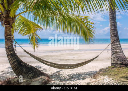 Empty hammock between palm trees on tropical beach in Thailand