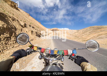 Motorcycling the Srinagar Leh Highway, a high altitude road that traverses the great Himalayan range, Ladakh, India. Mans hands on the helm of the Roy Stock Photo