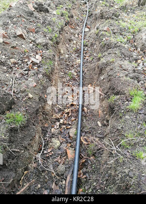 Laying of the sprinkler system of the pipeline in the ground trenches for the underground irrigation system, irrigation system, land municipal works in the late autumn in the park Stock Photo