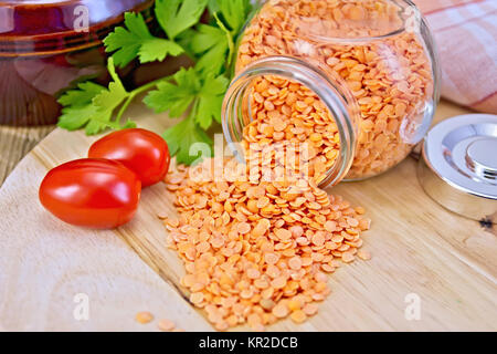 Lentils red in glass jar with tomatoes on board Stock Photo