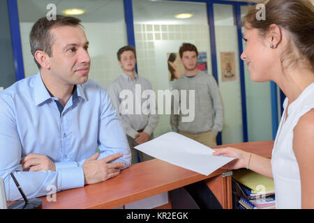 Lady handing form to man at reception desk Stock Photo