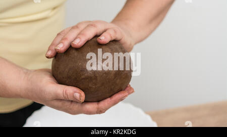 Detail of female hands holding a ball of brown dough. Kneading of sweet aromatic pastry for traditional Christmas gingerbreads. Stock Photo