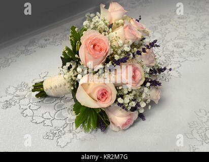 Photo of a small, romantic nosegay bridal bouquet with pink roses, baby's breath, sprigs of lavender, lace and pearls. Perfect for a vintage wedding! Stock Photo