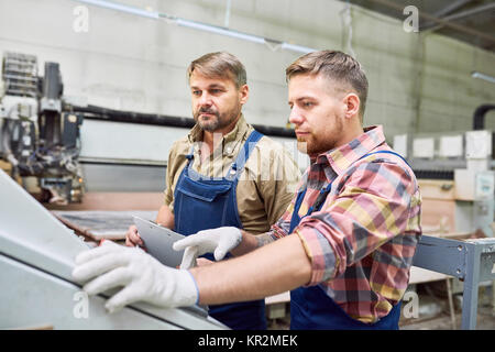 Two Workers Operating Machines at Factory Stock Photo