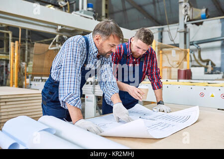 Workers Looking at Plans Stock Photo