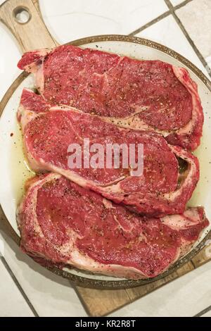 raw new york steaks on cutting board seasoned Stock Photo