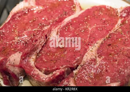 raw new york steaks on cutting board seasoned Stock Photo