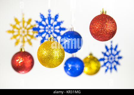 Beautiful Christmas and New Year colorful background. Close up of red, blue, golden shining festive balls hanging on glossy silver ropes isolated on w Stock Photo