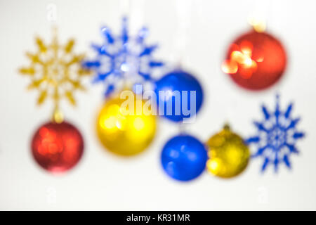 Beautiful Christmas and New Year colorful background. Close up of blurry red, blue, golden shining ornaments hanging on glossy silver ropes isolated o Stock Photo