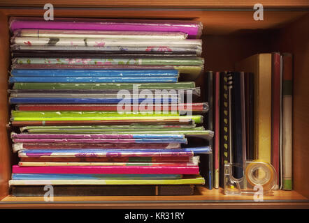 Colorful children's books and notebooks on shelf in closet. Stock Photo