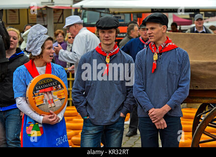 Dutch cheese girl with a Gouda cheese truckle and two cheese boys, cheese market Gouda, Netherlands Stock Photo