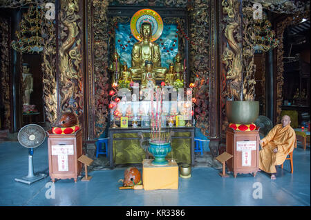 Buddhist monk sits inside the Vinh Trang Pagoda. This pagoda is one of the most beautiful and famous in the Mekong delta. Stock Photo