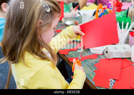 2 year old blonde girl cutting paper with blue children's scissors Stock  Photo - Alamy