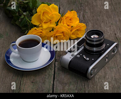 the ancient film camera, bouquet and coffee on an old wooden table, a still life Stock Photo