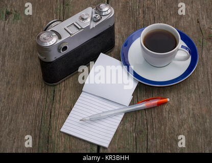 still life the old camera, a notebook and coffee, on an old table Stock Photo