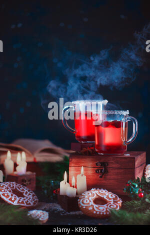 Two cups of berry hot drink in a night scene with gingerbread and candles. Holiday cooking concept. Copy space. Stock Photo