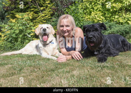 Smiling woman with dogs on the lawn Stock Photo