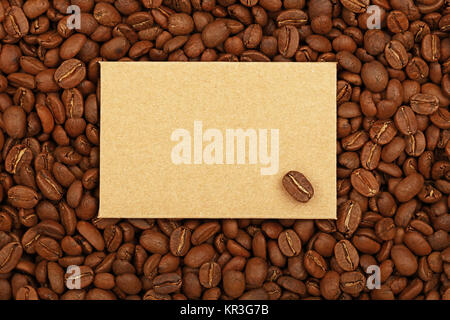 Close up blank brown kraft paper sign with copy space on background of roasted coffee beans, elevated top view, directly above Stock Photo
