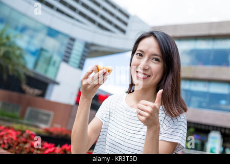 Woman having egg tart and showing thumb up Stock Photo