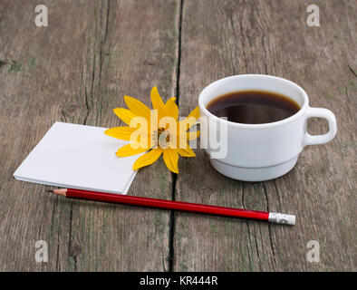 cup of coffee, pencil with paper and a yellow flower Stock Photo